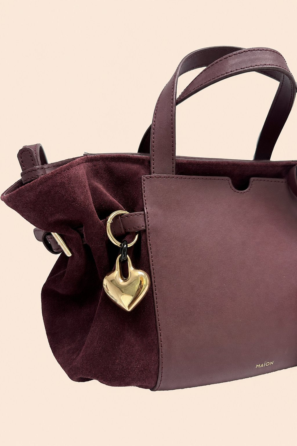 Charm cœur en métal doré Maïon, accroché à un sac en cuir velours bordeaux