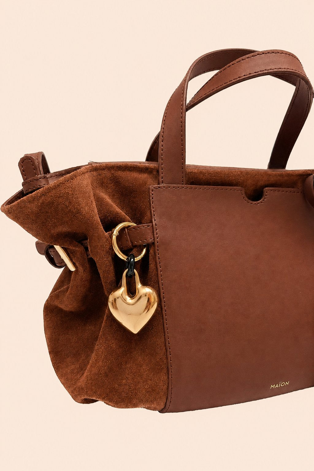 Charm cœur en métal doré Maïon, accroché à un sac en cuir velours marron