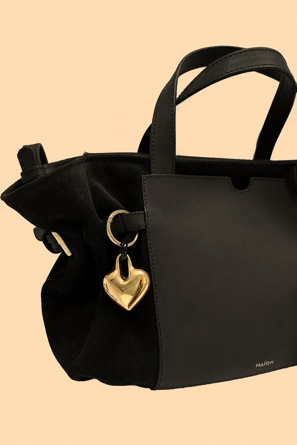 Charm cœur en métal doré Maïon, accroché à un sac en cuir velours noir