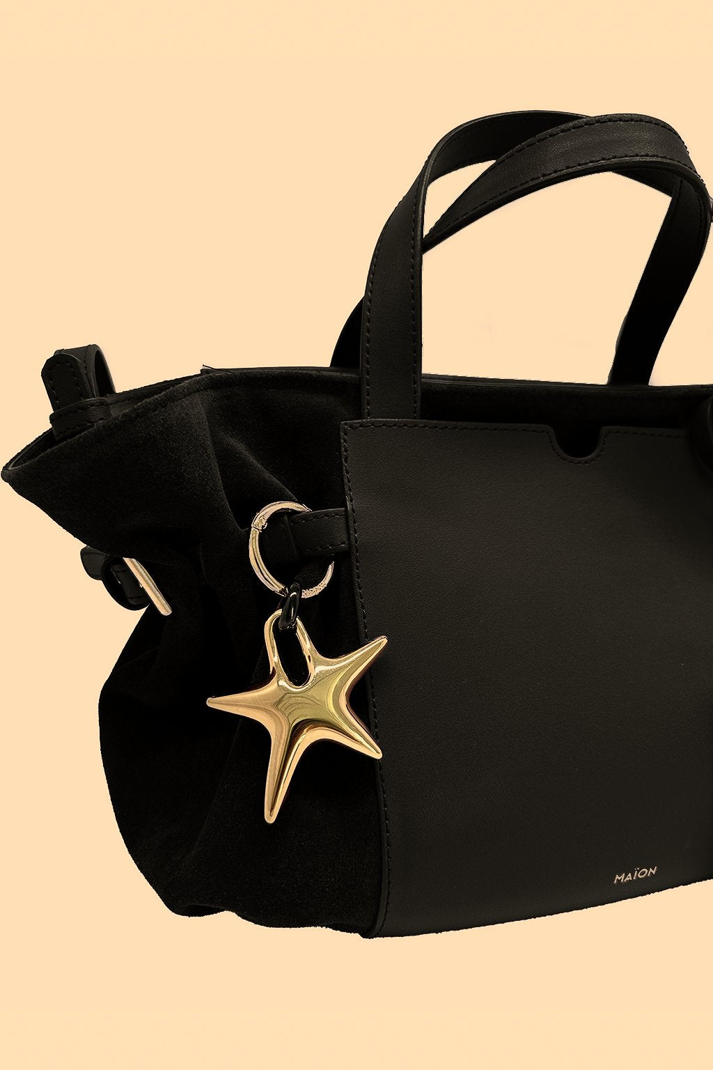 Charm étoile en métal doré Maïon, accroché à un sac en cuir velours noir
